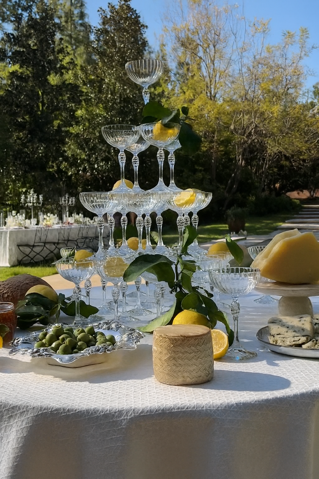Fontana di champagne a cascata su tavolo allestito con limoni freschi, fiori bianchi e tovaglia bianca per eventi e cerimonie